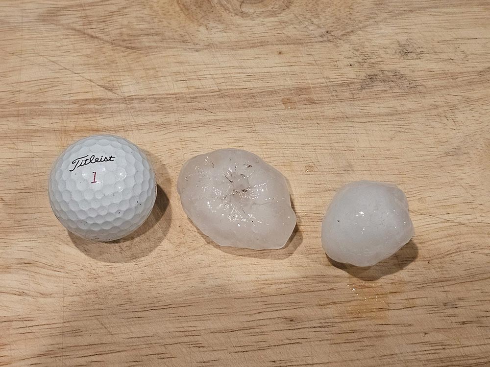 Hailstone next to a golf ball for size comparison